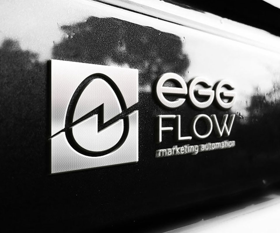 Logo EggFlow ở biến thể một màu, dập nổi ánh bạc trên bề mặt tối
