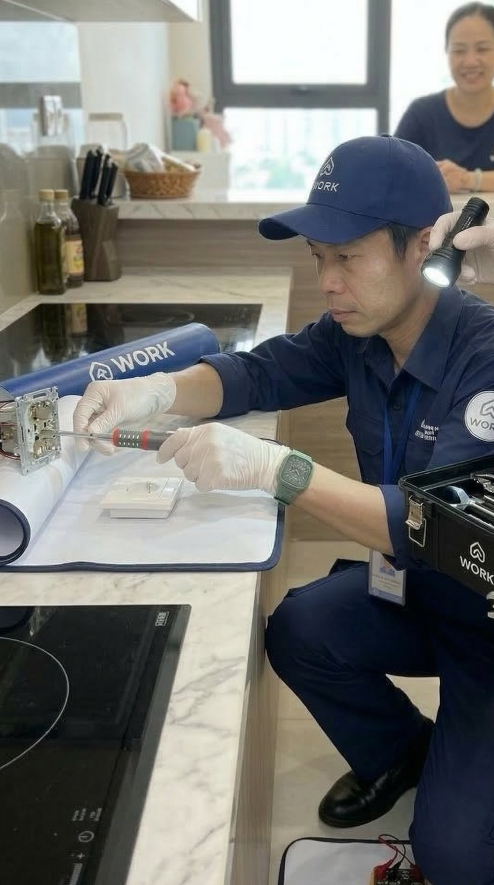 Sửa thiết bị bếp Kỹ thuật viên kythuat.work kiểm tra bếp từ trên mặt bàn đá của căn hộ