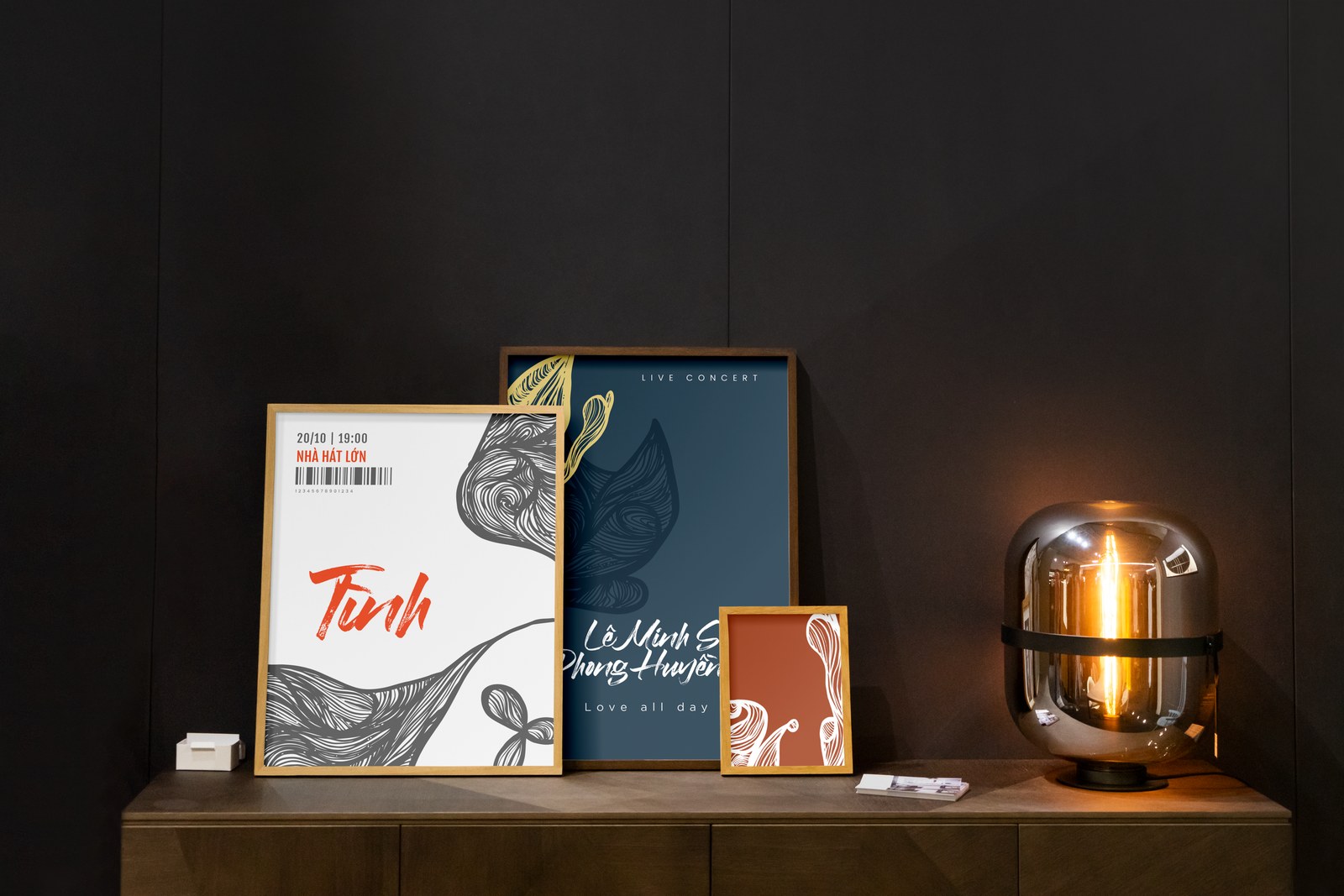 Bộ poster album Tình đóng khung đặt trên mặt tủ gỗ cạnh chiếc đèn bàn